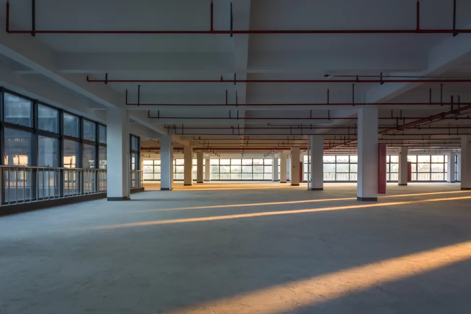 Large empty office building floor with columns and golden hour light.